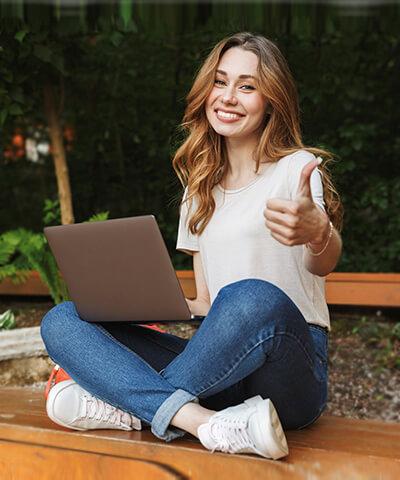Ventajas para particulares - Joven chica sonriendo sentada utilizando un portátil Ventajas para particulares - Joven chica sonriendo sentada utilizando un portátil