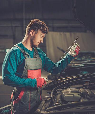Ventajas de  Seguro Multirriesgo Industrial - Mecanico revisando el nivel de aceite de una furgoneta en un taller de coches Ventajas de  Seguro Multirriesgo Industrial - Mecanico revisando el nivel de aceite de una furgoneta en un taller de coches
