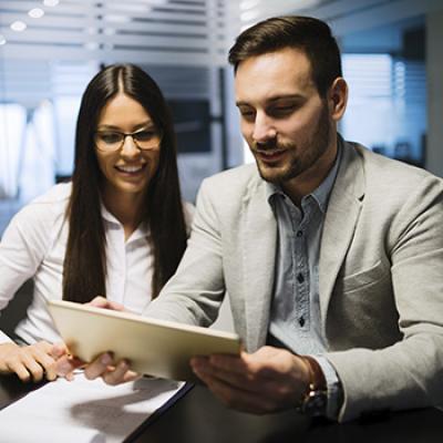 Informe de mercados - Dos personas de negocios con traje utilizando la tablet para ver informes de carteras Informe de mercados - Dos personas de negocios con traje utilizando la tablet para ver informes de carteras
